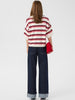 Model trägt Gestuz GZTaia Polo Pullover Egret/Cabernet/Poinsettia Streifen in Rot, Bordeaux und Ecru zu einer dunkelblauen Jeans Rückansicht